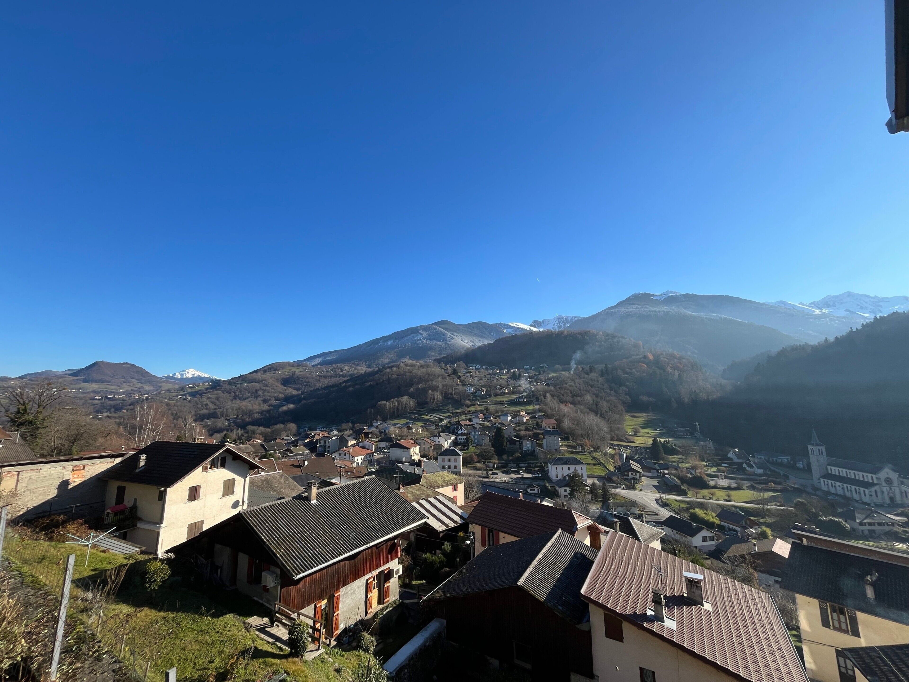 A village with traditional houses, a church, and mountains in the background.