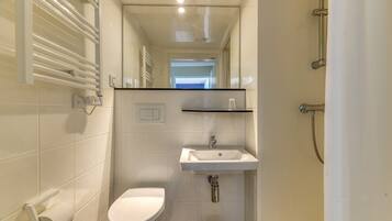 A bathroom with a toilet, sink, mirror, and towel rack.