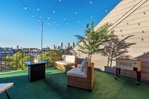 A rooftop terrace with a city view, outdoor seating, and a Coca-Cola branded cooler.