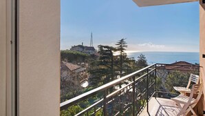 Uma varanda com vista para o mar, com guarda-corpo e algumas cadeiras.