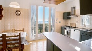 Uma cozinha com área de jantar, vista pela porta de vidro e um relógio na parede.
