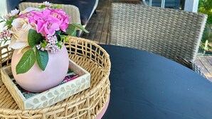 A covered porch with wicker furniture, a wicker basket with a vase of flowers, and a view of the outdoors. - Noosa Heads House. Resort style pool, surrounded by tropical gardens. Location! (Noosa Heads)