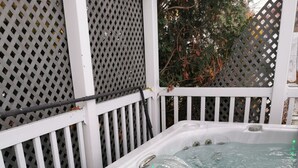 A hot tub with a white exterior, surrounded by a white fence with a lattice design. - Fully furnished house for rent for 6 to 8 people (Sainte-Thérèse)