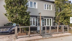 A two-story building with a gated entrance, a parked car, and a small tree in front. - Fully furnished house for rent for 6 to 8 people (Sainte-Thérèse)