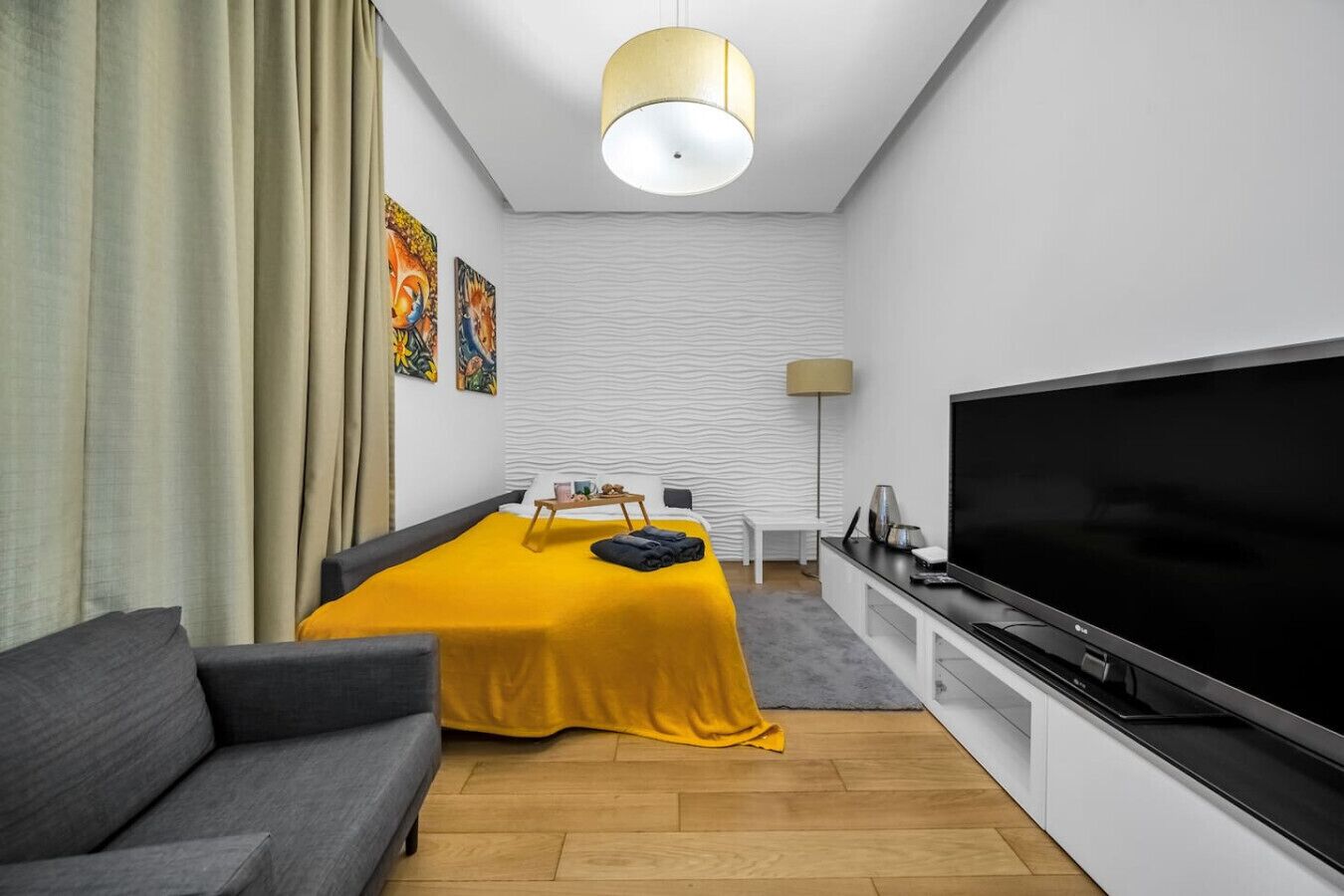 Una habitación de hotel moderna con una cama, un sofá, un televisor y un escritorio.