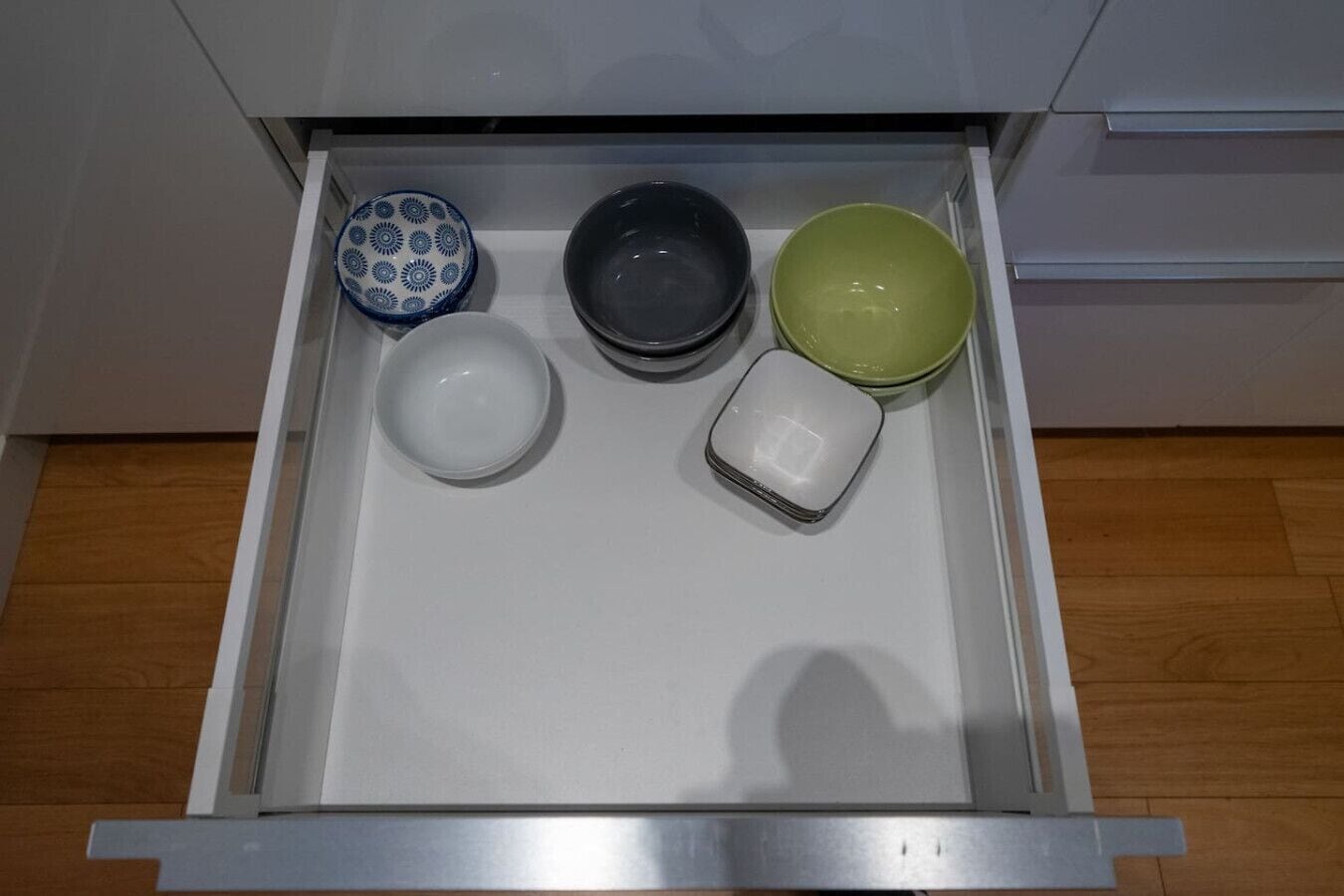 A kitchen drawer with four bowls and a salt shaker.