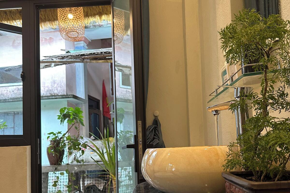 A modern bathroom with a marble countertop, a large mirror, and a potted plant.