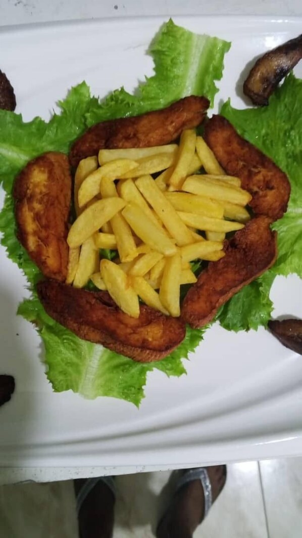 Une assiette de nourriture composée de frites et de viande, le tout servi sur un lit de laitue.