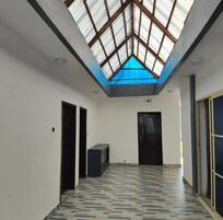 A hallway with a skylight, tiled floor, and black doors.