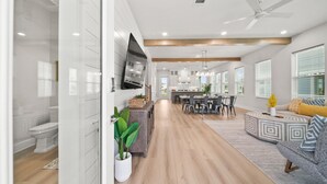 Una cocina moderna con comedor, una sala de estar con sofá y un amplio ventanal con persianas.
