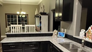 A modern kitchen with granite countertops, black cabinets, and a central island.