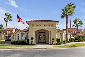 A Club House with a red-tiled roof, an American flag, and palm trees. - Magical Disney Retreat | Lake Berkley Resort & Pool (Kissimmee)