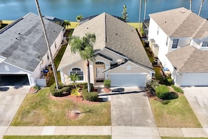 A residential area with houses, a driveway, and a body of water in the background. - Magical Disney Retreat | Lake Berkley Resort & Pool (Kissimmee)
