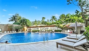 A swimming pool with lounge chairs and a stone wall.