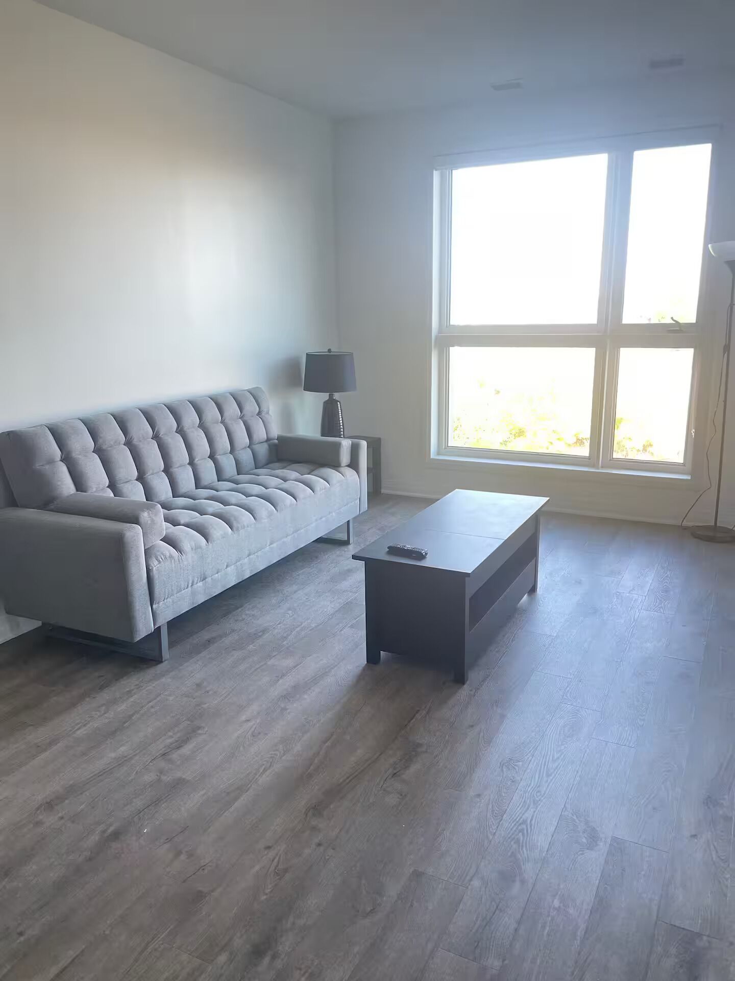 A modern living room with a grey sofa, a small table, and a floor lamp.