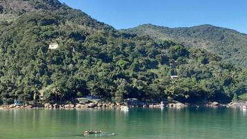 Un lago tranquilo con un bote, rodeado de verdes colinas y algunos edificios.