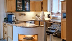 A compact kitchen with wooden cabinets, a built-in stove, and a bar stool. - Nice home in Fohnsdorf with sauna (Fohnsdorf)