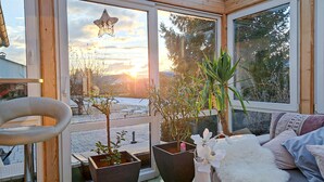 A cozy room with a large window, a sofa, a chair, and several potted plants. - Nice home in Fohnsdorf with sauna (Fohnsdorf)