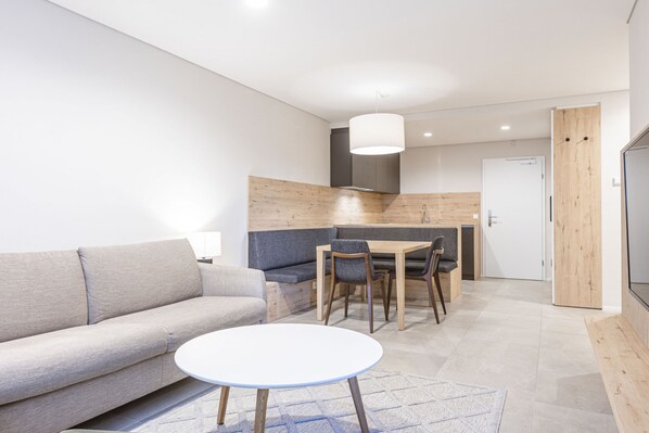 A modern living room with a sofa, a round table, and a dining area with chairs and a table.
