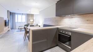 A modern kitchen with dark cabinets, a wooden countertop, and a built-in oven. - Apartment Near ski Area (Treffen)
