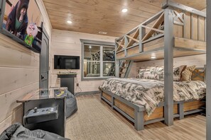 A bedroom with bunk beds, a TV, a desk with a game console, and a window. - Sleeps 18, Private Heated Indoor Pool, Theater, Hot Tub, 20 Min to Dollywood (Sevierville)