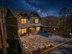 A two-story house with a stone facade, green trim, and a covered patio area. - Sleeps 18, Private Heated Indoor Pool, Theater, Hot Tub, 20 Min to Dollywood (Sevierville)