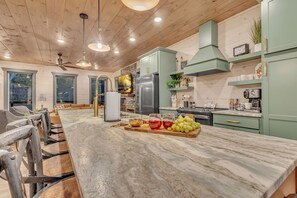A modern kitchen with a marble island, green cabinets, and a built-in stove.