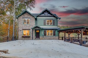 A two-story stone house with a green roof and a covered patio area. - Sleeps 18, Private Heated Indoor Pool, Theater, Hot Tub, 20 Min to Dollywood (Sevierville)