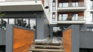 A modern building with a concrete staircase leading to a wooden door. - Modern City Home w. A/C (București)