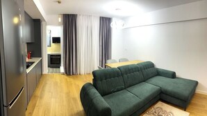 A modern apartment with a kitchen, dining area, and a green sofa. - Modern City Home w. A/C (București)