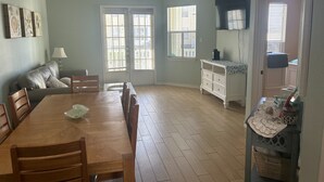 Uma sala de jantar ampla com uma mesa e cadeiras de madeira, um sofá e um armário com objetos decorativos.