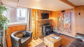A cozy living room with a fireplace, leather sofa, and wooden walls. - Garden Bodega on Sunset Ridge, Near Downtown, Hot tub, all with Panoramic View (Spokane)