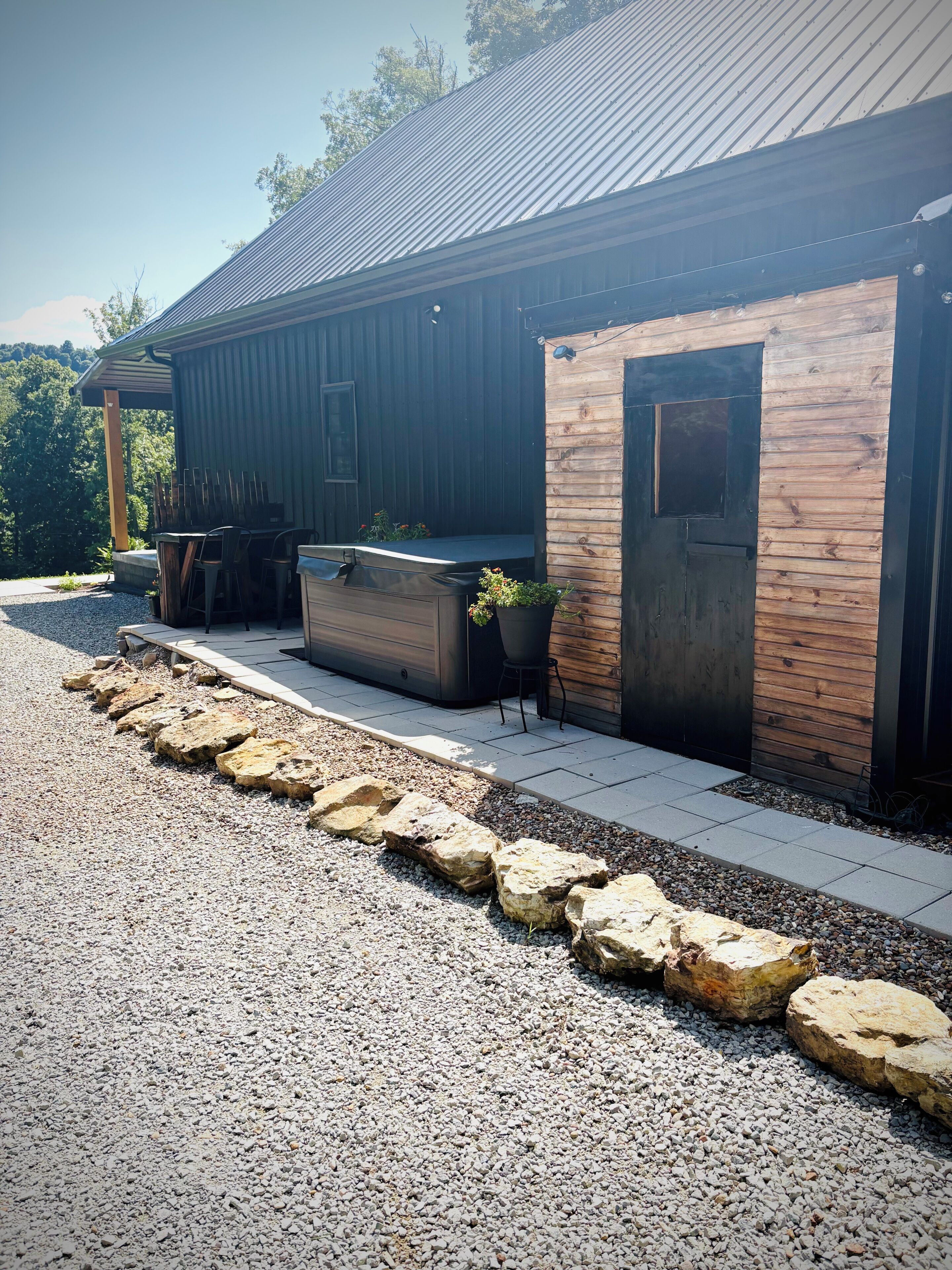 Un bâtiment avec une allée en gravier, une terrasse en bois, un espace salon extérieur et une porte.