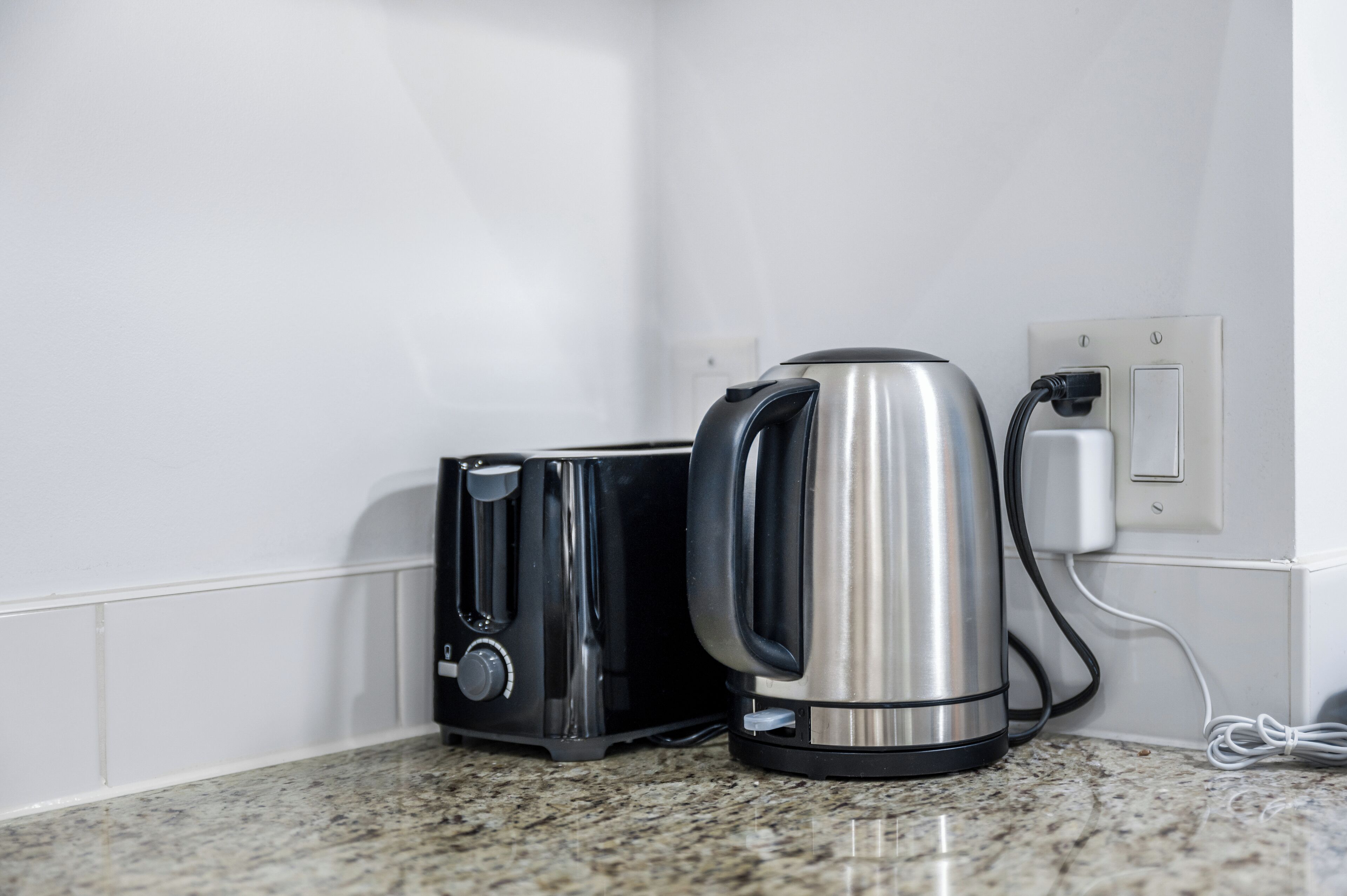 Een keuken met een broodrooster en een waterkoker, aangesloten op een stopcontact.