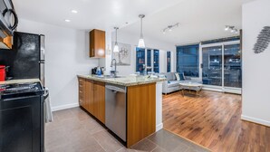A modern kitchen with a central island, wooden cabinets, and a built-in dishwasher.