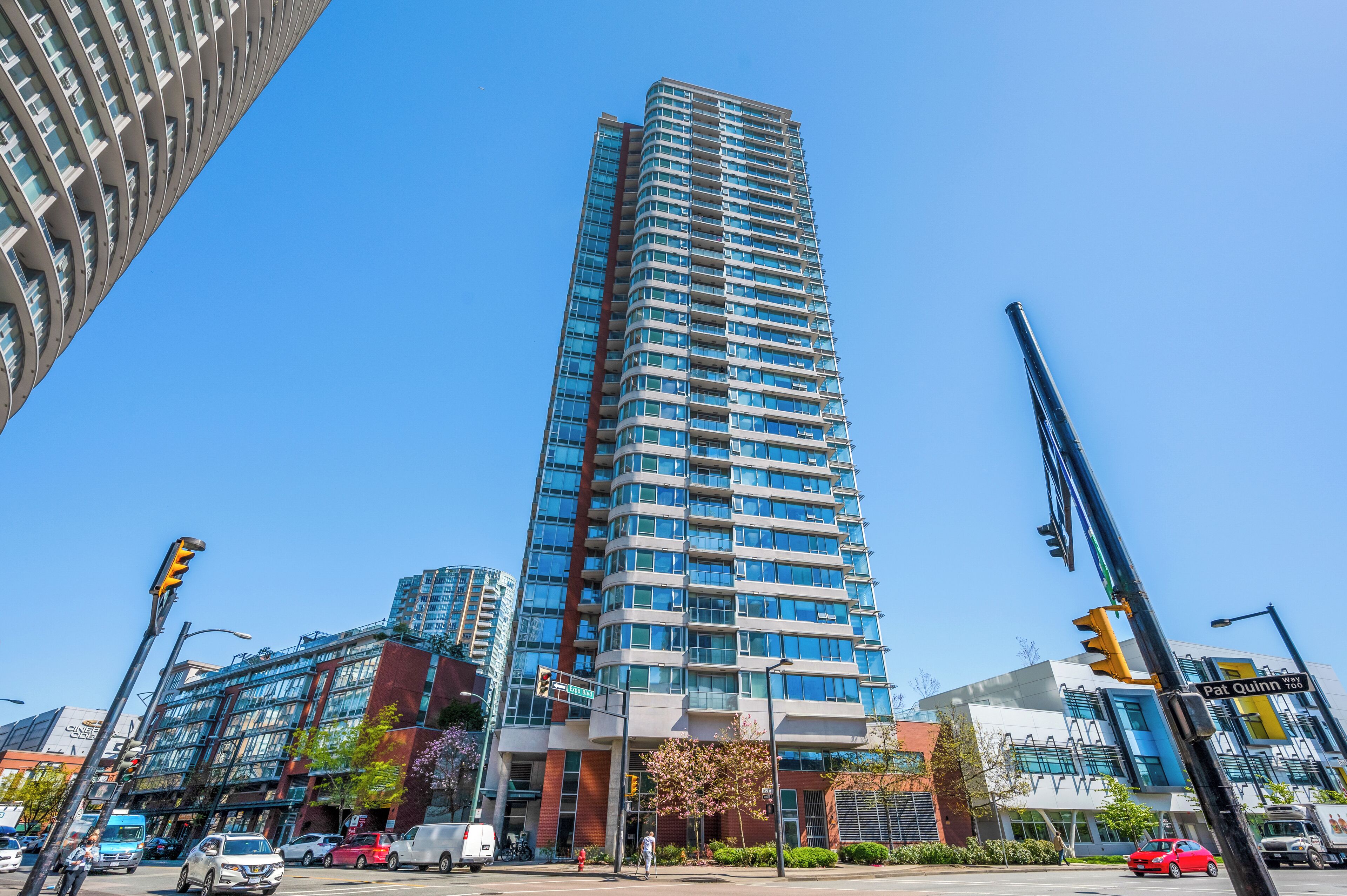 Een hoog, modern appartementencomplex met een gebogen gevel, gelegen op een levendige stedelijke kruising.