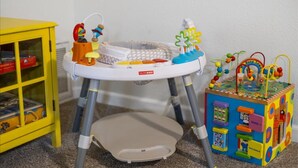 Un centre d’activités pour bébés comprenant un marchepied, un panier et des jouets.
