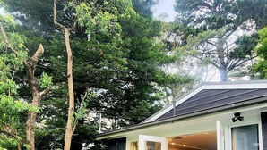Une maison dotée d’une terrasse, d’un coin repas et d’une cuisine visible à travers des portes vitrées.