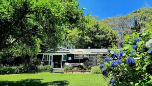 Une maison dotée d’un porche, entourée d’une végétation luxuriante et d’une pelouse bien entretenue.