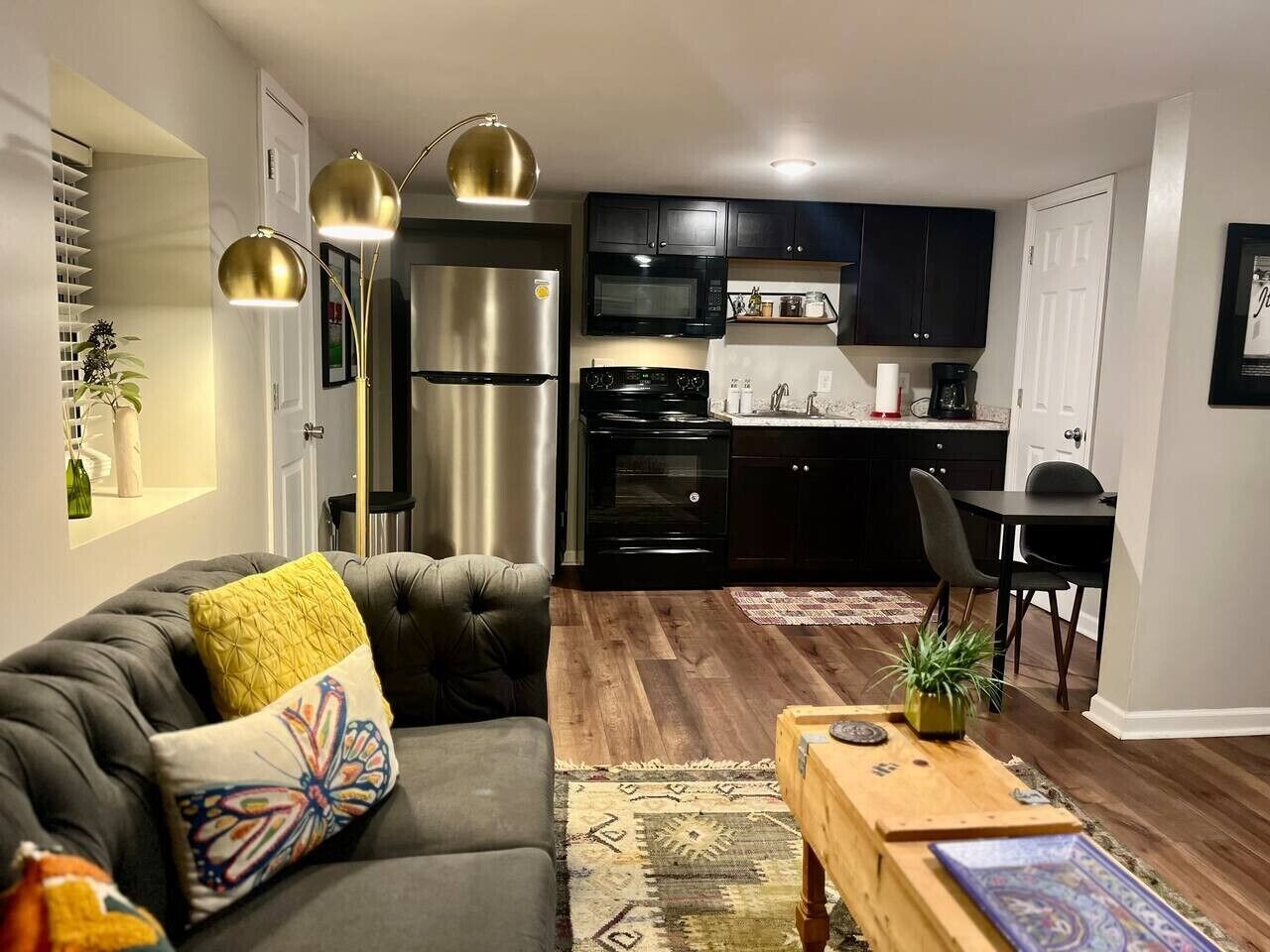 A modern kitchen with stainless steel appliances, a dining area with a table and chairs, and a living room with a sofa and a coffee table.