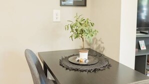 A dining area with a table, chairs, a potted plant, and two framed pictures on the wall.