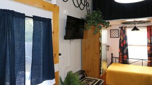 A room with a bed, a TV mounted on the wall, and a ceiling fan. - Charming Backyard Studio/Tiny Home in beautiful Jacksonville/OP  (Jacksonville)