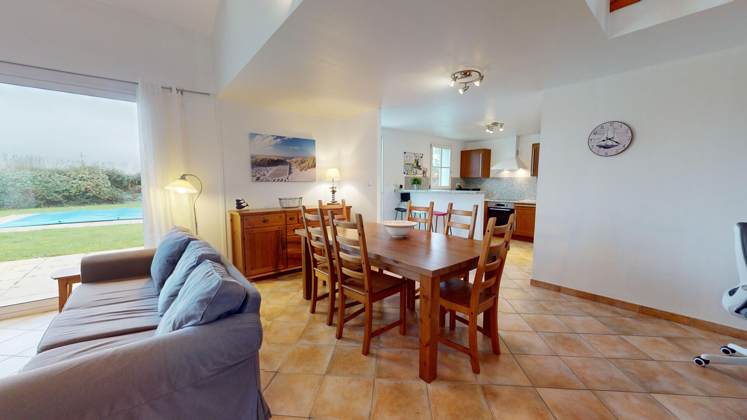 Amplia sala de estar con una mesa y sillas de comedor, un sofá y una cocina al fondo.