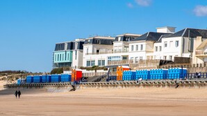 A coastal building with multiple balconies and a sandy beach in the foreground.