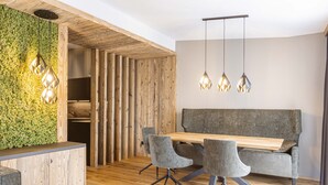 Un interior moderno con un mostrador de recepción de madera, una pared verde, un sofá gris y una mesa de comedor de madera con sillas.