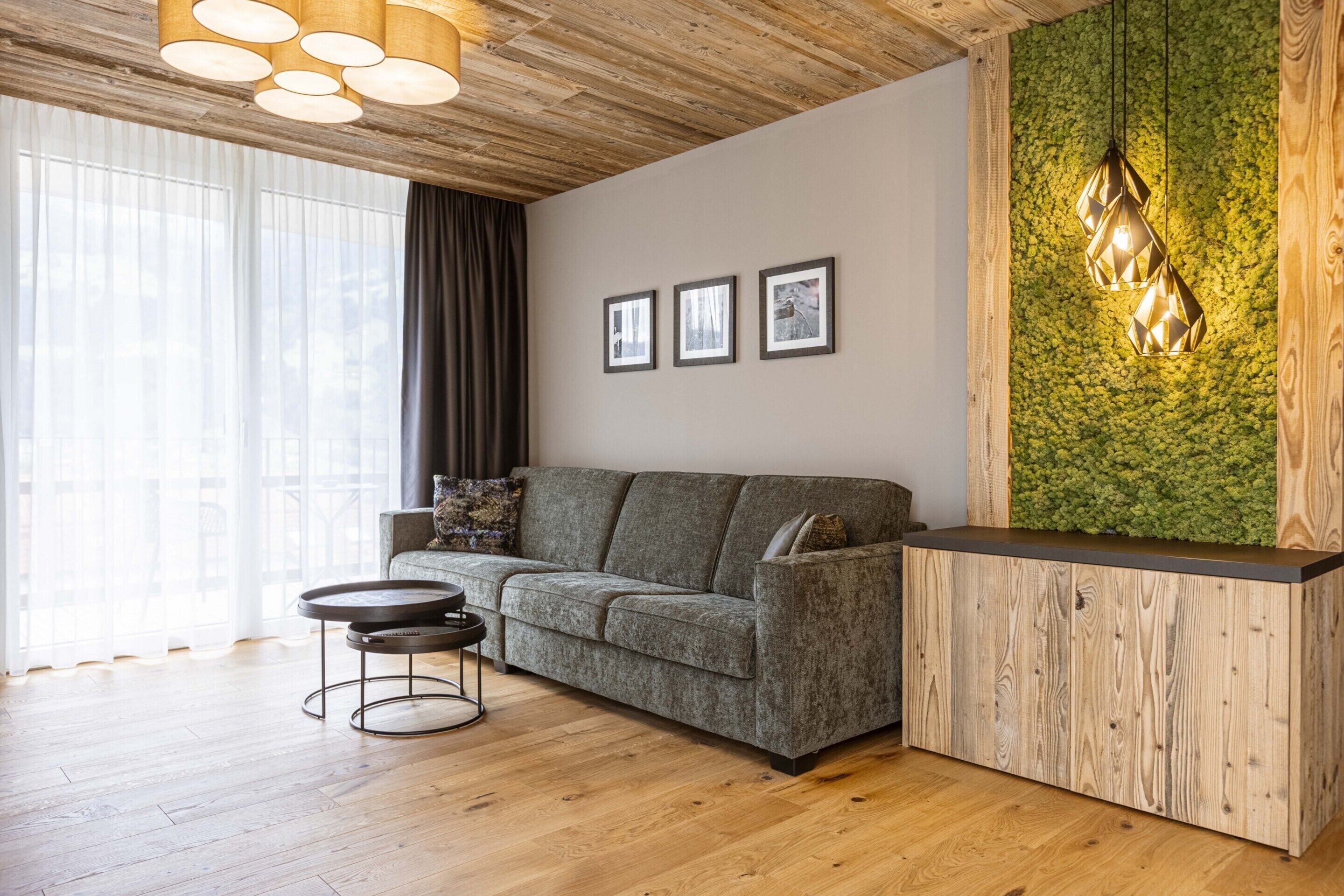 A modern living room with a grey sofa, a round coffee table, and a wooden reception desk.