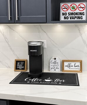 Una cocina moderna con una cafetera Keurig, un cartel de prohibido fumar y decoración con temática de café.
