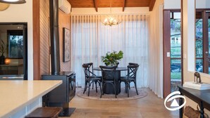 A modern kitchen with a round dining table, black chairs, and a chandelier. - 'Linden Rise'  cosy farmhouse, peace & charm with views  for miles. (Pakenham Upper)