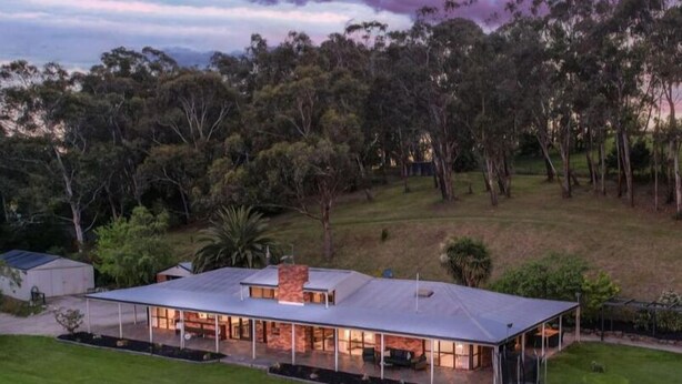 A modern house with a large glass facade, a covered outdoor area, and a well-maintained lawn. - 'Linden Rise'  cosy farmhouse, peace & charm with views  for miles. (Pakenham Upper)