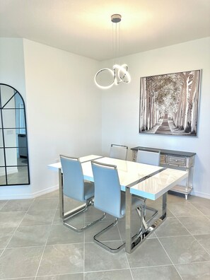 Enjoy meals in this stylish dining area with a rectangular table and four chairs, surrounded by a large artwork and natural light.
